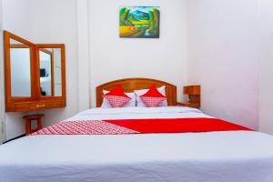 a bedroom with a white bed with red sheets and a mirror at Super OYO 3042 Griya Karangsalam Indah in Purwokerto