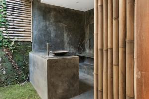 uma casa de banho com uma tigela de pedra sobre um balcão de betão em Villa Nido Canggu em Canggu
