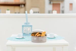 a bowl of cookies on a table with cups and saucers at Romantic Room in Monopoli