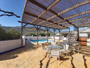 a patio with tables and chairs and a pool at Casa Pino Solo in Iznájar