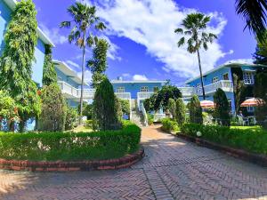 a building with palm trees and a brick walkway at Hotel Megha-Traveller's Village in Nepālganj
