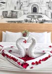 Abadi Hotel Malioboro Yogyakarta by Tritama Hospitality في يوغياكارتا: اثنين من البجعات البيضاء ملقاة على سرير بقلوب