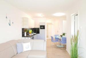 a white living room with a white couch and a kitchen at Baabe Villen Ensemble FeWo 11 Blau in Baabe