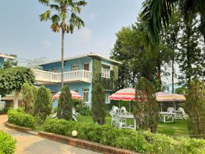 una casa azul con mesas y sombrillas blancas en Hotel Megha-Traveller's Village, en Nepālganj