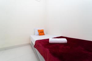 biały pokój z łóżkiem z pomarańczową poduszką w obiekcie KoolKost @ Harapan Indah w mieście Bekasi