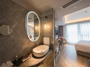 a bathroom with a sink and a bed and a mirror at Mercure Hangzhou West Lake in Hangzhou