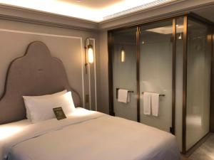 ein Schlafzimmer mit einem weißen Bett und einer Dusche in der Unterkunft Mercure Hangzhou West Lake in Hangzhou