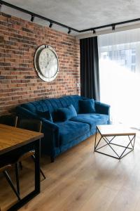 a blue couch against a brick wall with a clock at Apartament Małopanewska Wrocław Centrum in Wrocław