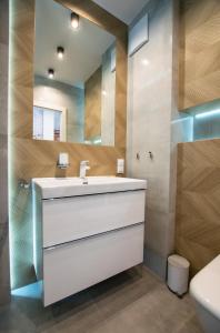a bathroom with a white sink and a mirror at Apartament Małopanewska Wrocław Centrum in Wrocław