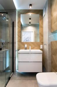 a bathroom with a white sink and a mirror at Apartament Małopanewska Wrocław Centrum in Wrocław