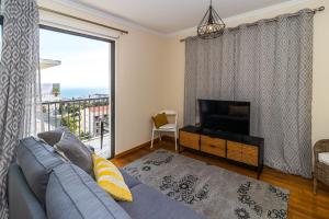 a living room with a couch and a tv and a window at Acacia Apartment by Atlântica in Funchal