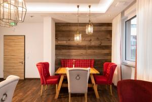 a dining room with a wooden table and red chairs at Allgäu Art Hotel in Kempten
