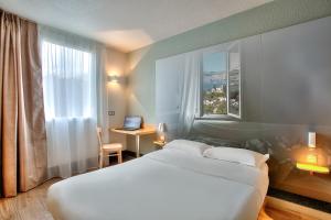 ビオットにあるB&B HOTEL Antibes Sophia Antipolisのベッド、デスク、ノートパソコンが備わるホテルルームです。