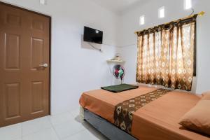 a bedroom with a bed and a door and a television at Java Homestay in Yogyakarta