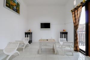 Habitación con sillas blancas, mesa y TV. en Java Homestay, en Yogyakarta