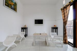 a room with white chairs and a table and a tv at Java Homestay in Yogyakarta