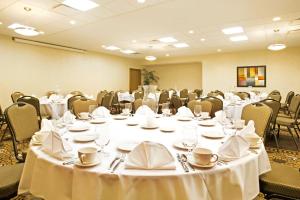 una sala de conferencias con mesas y sillas y ropa de cama blanca en Holiday Inn Battle Creek, an IHG Hotel, en Battle Creek