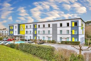 - un grand bâtiment blanc avec une piscine en face dans l'établissement B&B HOTEL Antibes Sophia Antipolis, à Biot