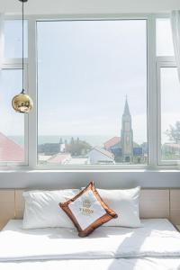 a bed with white pillows in front of a window at Yurii Hotel in Phan Thiet