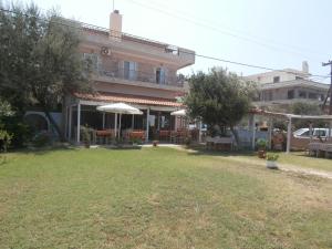 a building with a yard with chairs and umbrellas at Hotel Almira in Agia Triada