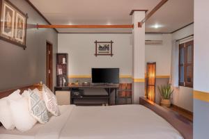 Un dormitorio con una cama y un escritorio con televisión. en Sanctuary Hotel Luang Prabang, en Luang Prabang