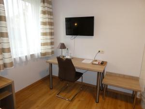 a desk with a chair and a television on a wall at Hotel Munzert in Hof