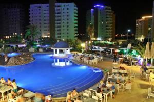 una piscina con gente sentada alrededor de ella por la noche en BLUE apartment in 5* Ceasar Resort, en Trikomo
