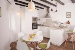 a kitchen with white cabinets and a white table and chairs at Apartment A&E in Šibenik