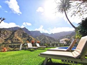 a group of chairs sitting on a lawn with a view of mountains at Apartamentos Los Telares in Hermigua