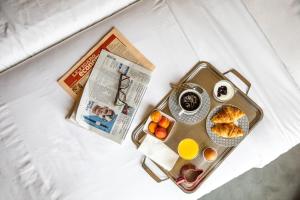 bandeja con alimentos para el desayuno y un periódico en una cama en Le Petit Belloy en París