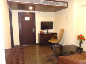 een kamer met een bureau, een televisie en een stoel bij Pride Ananya Resorts in Puri