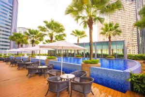 a swimming pool with tables and chairs and palm trees at Yemala Suites at Vortex KLCC in Kuala Lumpur