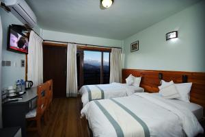 a hotel room with two beds and a window at The Lapsi Tree in Nagarkot