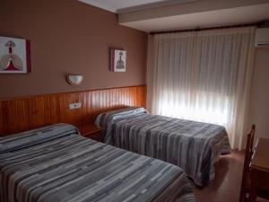 a hotel room with two beds and a window at Hostal Durá in Torrellano