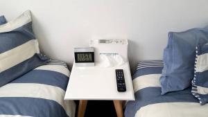 a room with two beds and a table with a clock at Shima Stay holoholo in Zamami