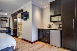 a bedroom with a bed and a kitchen with a counter at The Nightingale Guesthouse in Bloemfontein