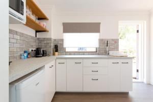 una cucina bianca con mobili bianchi e una finestra di Quokka at White Gum Lodge a Fremantle