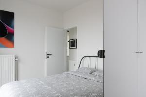 een witte slaapkamer met een bed en een kast bij Unieke Penthouse bij Brugge in Blankenberge