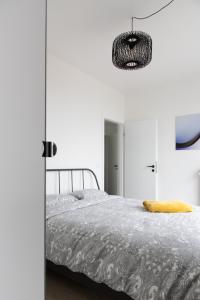 een witte slaapkamer met een bed en een kroonluchter bij Unieke Penthouse bij Brugge in Blankenberge