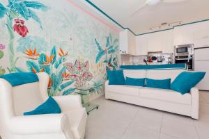 salon z 2 białymi krzesłami i tropikalnym freskiem w obiekcie First line sea, luxury penthouse, sea and sunset view Vivenda Vacational Guayero 618 w mieście Los Cristianos