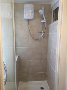 a bathroom with a shower with a shower head at Chalet with hot tub room in Clanfield