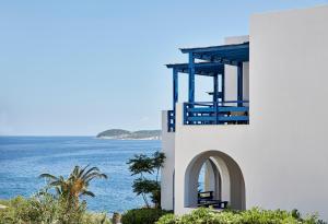 a white building with a balcony overlooking the ocean at Andros Holiday Hotel in Gavrio