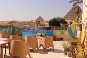 a beach with chairs, tables, chairs and umbrellas at Pyramids Overlook Inn in Cairo