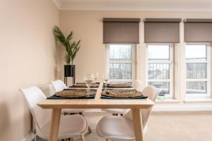 a dining room with a wooden table and white chairs at The Lucas - Donnini Apartments in Ayr