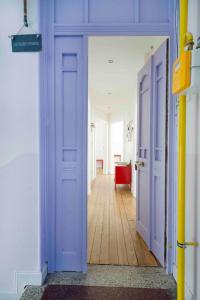 - un couloir avec des portes violettes et du parquet dans l'établissement Rock in Share - Le Saint-Pierre, à Metz