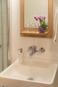bagno con lavandino, specchio e fiori di Landhotel Oßwald a Kirchheim am Ries