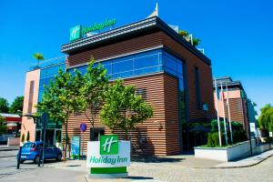 a building with a tree in front of it at Holiday Inn Bydgoszcz, an IHG Hotel in Bydgoszcz