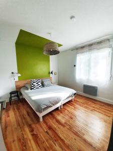 - une chambre avec un lit et un mur vert dans l'établissement La Maison Bisca, à Biscarrosse-Plage