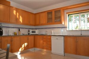 a kitchen with wooden cabinets and a white dishwasher at Paradise Beach Villa in Albufeira