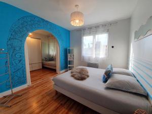 ビスカロッス・プラージュにあるLa Maison Biscaの青い壁のベッドルーム1室(大型ベッド1台付)